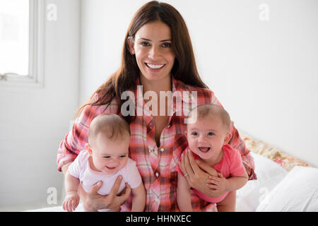 Kaukasische Mutter hält Baby Zwillingstöchter Stockfoto