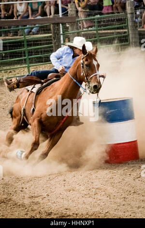 Cowgirl Reiten in der Nähe von Barrel im rodeo Stockfoto