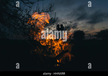 Silhouette des kaukasischen paar küssen in der Nähe von Feuer Stockfoto