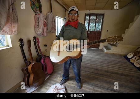 22. Juli 2016 San Bartolome, Ecuador: Gitarrenbauer Mann stehend mit einer fertigen Konzertgitarre in seinem Geschäft Stockfoto