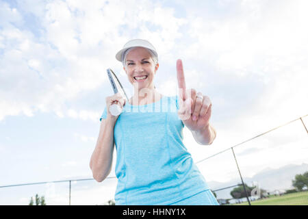 Kaukasische Frau mit Tennisschläger gestikulieren Nummer eins Stockfoto