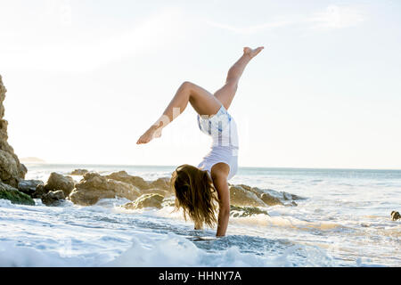 Kaukasische Frau tun Handstand am Strand Stockfoto