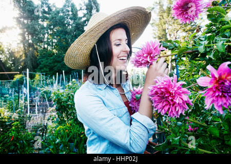 Kaukasische Frau riechende Blume im Garten Stockfoto