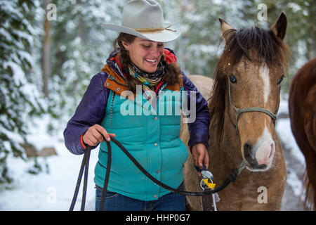 Lächelnd kaukasischen Frau Holding Zügel des Pferdes im winter Stockfoto