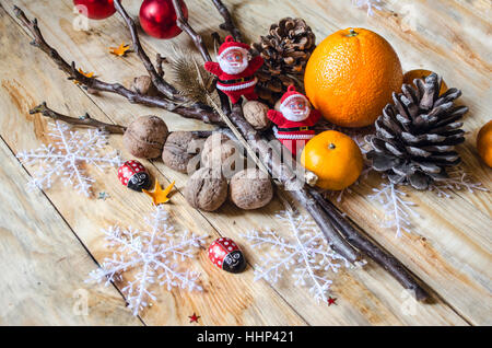 Plüsch Nikoläuse unter Zweigen mit Nüssen und Zitrusfrüchten Stockfoto