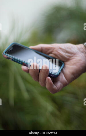 Der Mann hält PDA Smartphone im rechten senkrechten Grünen im Hintergrund Stockfoto