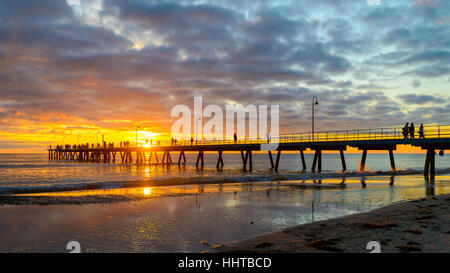 Menschen zu Fuß auf Glenelg Beach Pier bei Sonnenuntergang, South Australia Stockfoto