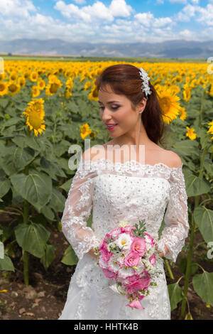 Schöne junge Braut posiert in einem Sonnenblumenfeld Stockfoto