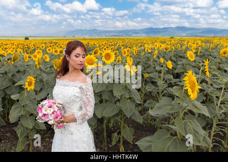 Schöne junge Braut posiert in einem Sonnenblumenfeld Stockfoto