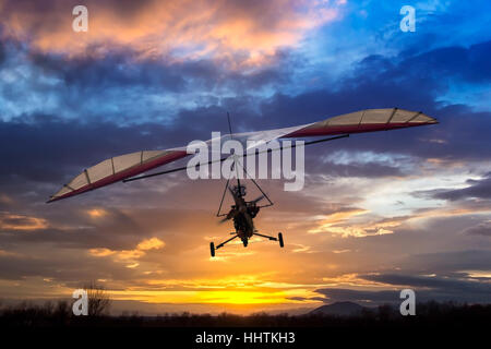 Motorisierte Hängegleiter fliegen in den Sonnenuntergang Stockfoto