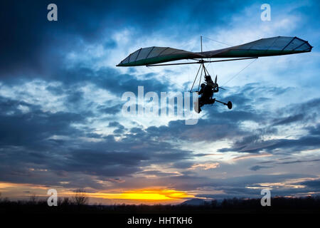 Motorisierte Hängegleiter fliegen in den Sonnenuntergang Stockfoto