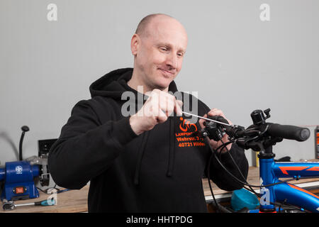 Fahrradmechaniker während der Inspektion bei einem Mountainbike in seiner Werkstatt. Stockfoto