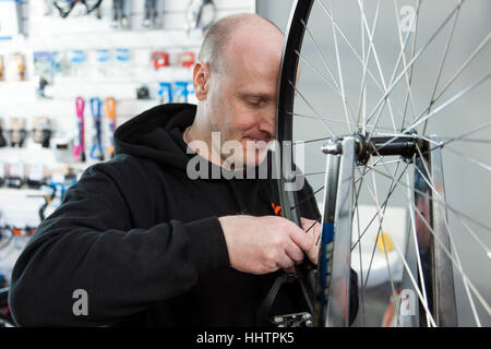 Fahrradmechaniker Zentrierung ein Hinterrad in seiner Werkstatt. Stockfoto