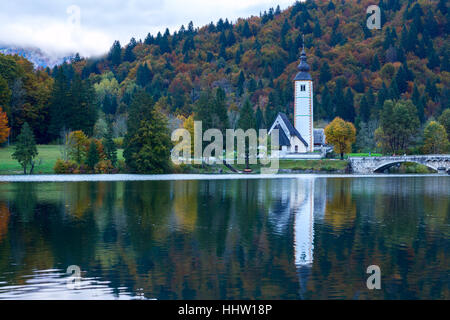 Kirche-Turm und Stein Brücke am Bohinj See im Bergdorf Ribicev Laz, Slowenien Stockfoto