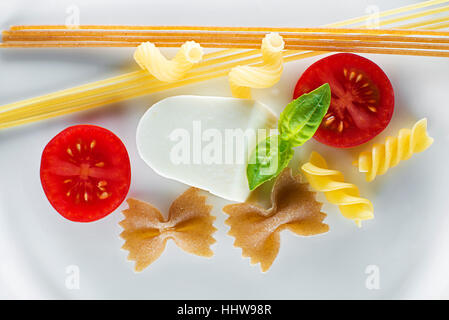 Trockene Nudeln mit Mozzarella und Tomaten auf weißem Hintergrund Stockfoto