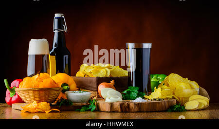 Bier, Cola und Kartoffel-Chips und Zutaten in Stillleben Stockfoto