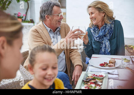 Gerne älteres Paar, toasten Weißweingläser Innenhof mittags Stockfoto