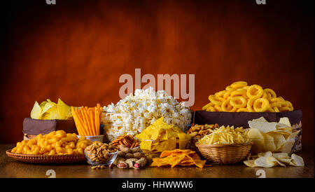 Verschiedene Arten von Snacks, Chips, Nüssen und Popcorn in Stillleben Stockfoto