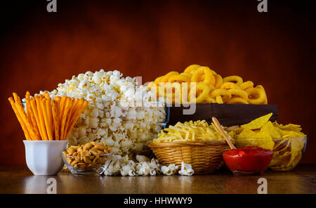 Abweichende Arten von Junk-Food, Popcorn, salzig-Sticks, salzige Cracker auf Holztisch im Still-Leben Stockfoto