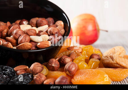 Getrocknete Früchte, Zitrone, Aprikose, Feigen und Nüssen in schwarze Platte auf einem hölzernen Hintergrund. Stockfoto