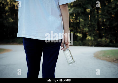 Teen Mädchen steht an einer Weggabelung mit einer Bierflasche Stockfoto