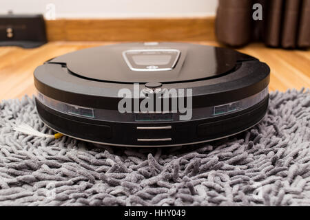 Roboter-Staubsauger auf Holz Parkett, Smart Vakuum, neue automatisieren Technologie Hausarbeit - Reinigung auf Teppich. Stockfoto