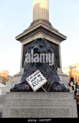 Ein Plakat neben einer der Löwen am Fuße des Nelson Säule auf dem Trafalgar Square von Demonstranten, die Teilnahme an einer Demonstration durch die Londoner Förderung der Frauenrechte im Zuge des Wahlergebnisses US platziert. Stockfoto