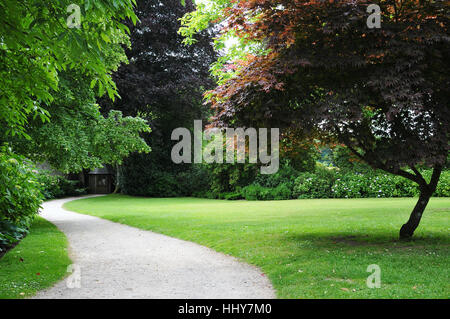 Reizvolle Aussicht auf einen Kiesweg Wicklung durch friedlichen grünen englischen Landschaftsgarten Stockfoto