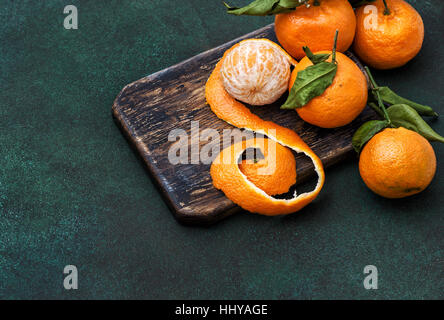 Mandarinen-Früchte. Orange Mandarine mit frischen Blättern auf rustikalen Holzküche board Stockfoto