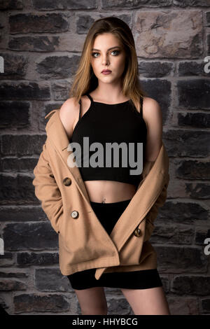 Portrait of Young Woman Blick in die Kamera, Studio Aufnahme mit Steinmauer Hintergrund Stockfoto