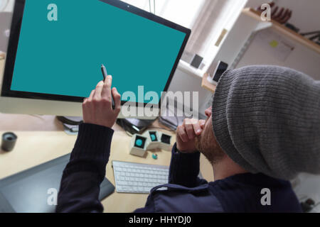 Web-Designer sitzt an seinem Schreibtisch hält seine digitalen Stift und ist bereit zu arbeiten auf seiner Website-Design-Projekt Stockfoto