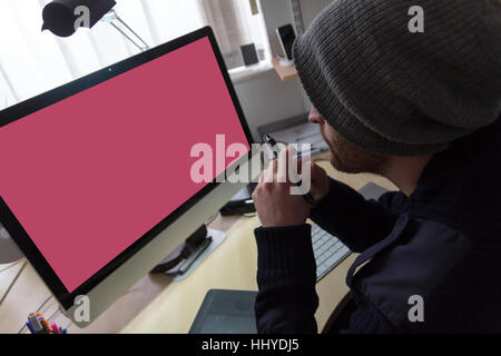 Web-Designer / Entwickler sitzt an seinem Schreibtisch hält seine digitalen Stift und ist bereit zu Beginn der Arbeit an seinem nächsten Projekt. Man überlegte, was er tun konnte nex Stockfoto