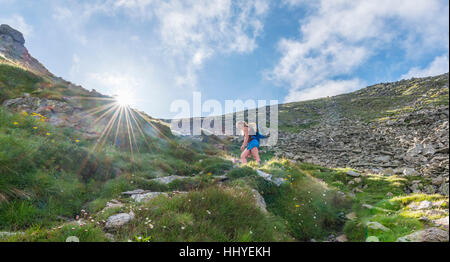 Weibliche Wanderer auf Fußweg in Bergen, Sonne scheint über Grat, aufsteigen, Greifenberg, Schladminger Tauern, Steiermark, Österreich Stockfoto