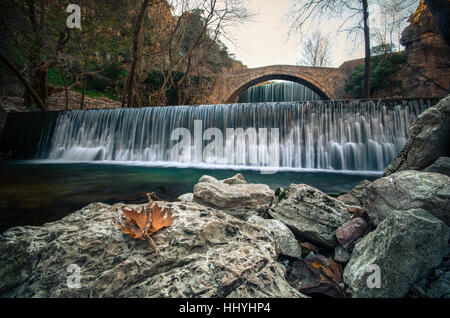 Paleokarya, alte, Stein, gewölbte Brücke zwischen zwei Wasserfälle. Trikala Präfektur, Thessalien, Griechenland Stockfoto