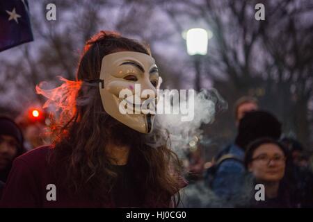 Demonstranten, die bei der Amtseinführung von Präsident Donald Trump in Washington, D.C. ein junger weißer Mann, der eine Guy Fawkes Maske atmet e-Zigarette Dämpfe, wie er beteiligt sich an Protestaktionen in einem Park. Stockfoto