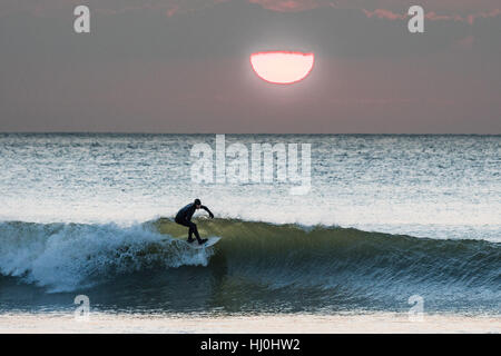 Aberystwyth Wales UK, Samstag, 21. Januar 2017 UK Wetter: nach einer eisigen, kalten Nacht mit Temperaturen weit unter Null, Surfer genießen Sie die Wellen bei Sonnenuntergang am Ende ein schöner Tag Sonnenstrahlen in Aberystwyth auf die Cardigan Bay Küste Westwales Foto Keith Morris / Alamy Live News Stockfoto