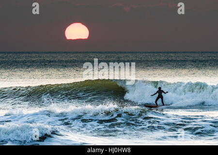 Aberystwyth Wales UK, Samstag, 21. Januar 2017 UK Wetter: nach einer eisigen, kalten Nacht mit Temperaturen weit unter Null, Surfer genießen Sie die Wellen bei Sonnenuntergang am Ende ein schöner Tag Sonnenstrahlen in Aberystwyth auf die Cardigan Bay Küste Westwales Foto Keith Morris / Alamy Live News Stockfoto