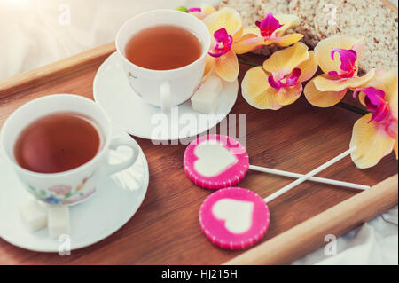 Frühstück im Bett in Valentinstag. Tasse Tee und süßen Bonbons. Liebe oder Urlaub Konzept. Stockfoto