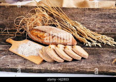 Dekoration mit Roggenbrot, getrockneten Kräutern und Mehl auf einem Holzsockel Stockfoto