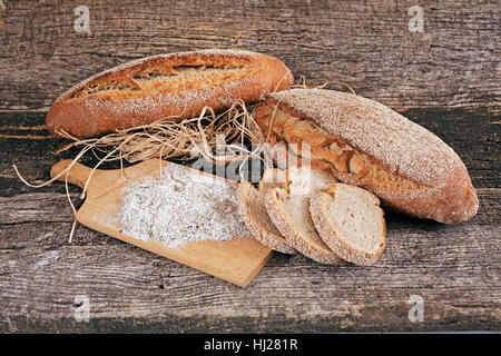 Dekoration mit Roggenbrot, getrockneten Kräutern und Mehl auf einem Holzsockel Stockfoto