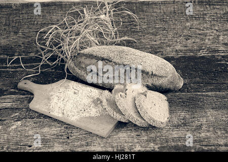 Dekoration mit Roggenbrot, getrockneten Kräutern und Mehl auf einem Holzsockel Stockfoto