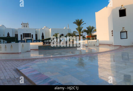 Hotel mit zweistöckigen Häusern im аrabic Stil mit weißen Wänden und Palmen an einem sonnigen Sommertag Stockfoto