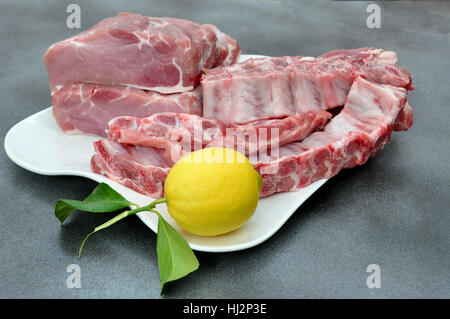 Tablett mit Schweinelende, Rippen und einer Zitrone Stockfoto