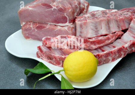 Tablett mit Schweinelende, Rippen und einer Zitrone Stockfoto