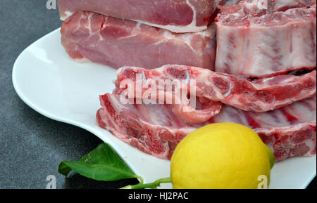 Tablett mit Schweinelende, Rippen und einer Zitrone Stockfoto