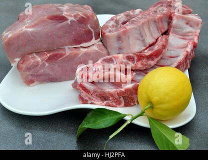 Tablett mit Schweinelende, Rippen und einer Zitrone Stockfoto