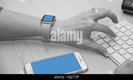 Support-Mitarbeiter über Tastatur eingeben. Aufnahme zeigt auch iWatch und iPhone. Stockfoto