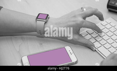 Support-Mitarbeiter über Tastatur eingeben. Aufnahme zeigt auch iWatch und iPhone. Stockfoto