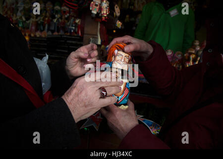 Touristen aus den USA beobachten Russkiy Toy mit dem Porträt von Donald Trump in Souvenir-Kiosk auf dem Roten Platz in Moskau, Russland Stockfoto