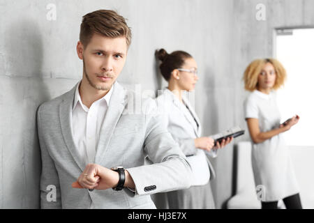 Zeit ist Geld. Während des Wartens auf ein Vorstellungsgespräch. Junger Mann seine Uhr stehen auf dem Flur außerhalb des Büros zu überprüfen. Stockfoto